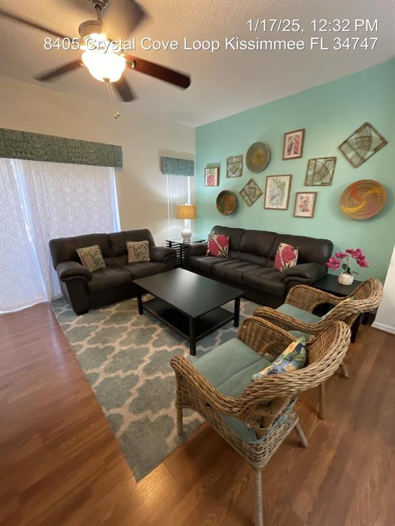 A living room features dark leather sofas, wicker armchairs, a coffee table, and wall decor — 8405 CRYSTAL COVE LOOP, KISSIMMEE, FL