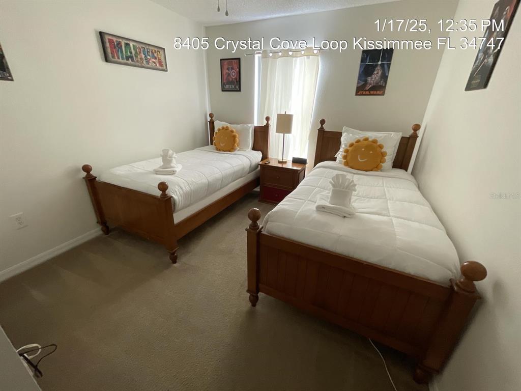 A bedroom features two twin beds with wooden frames, white bedding, and yellow sun pillows — 8405 CRYSTAL COVE LOOP, KISSIMMEE, FL