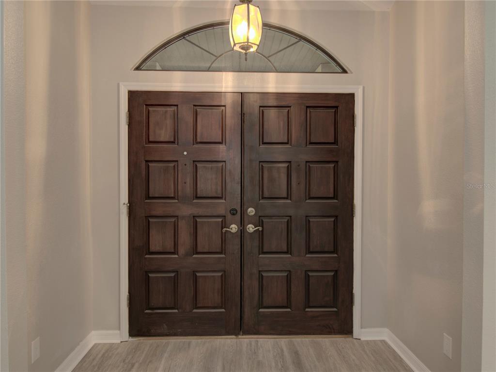 A double front door with a transom window sits in a neutral-walled entryway — 5360 SW 86TH LANE, OCALA, FL