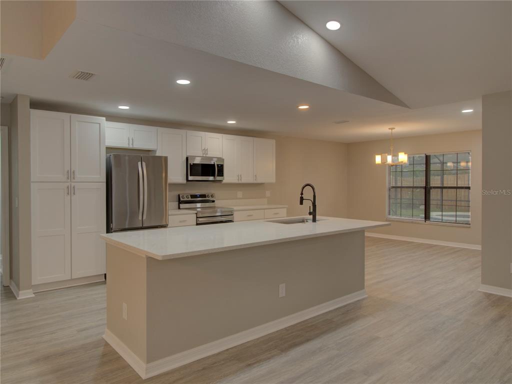 A modern kitchen features white cabinetry, stainless steel appliances, and a large central island — 5360 SW 86TH LANE, OCALA, FL