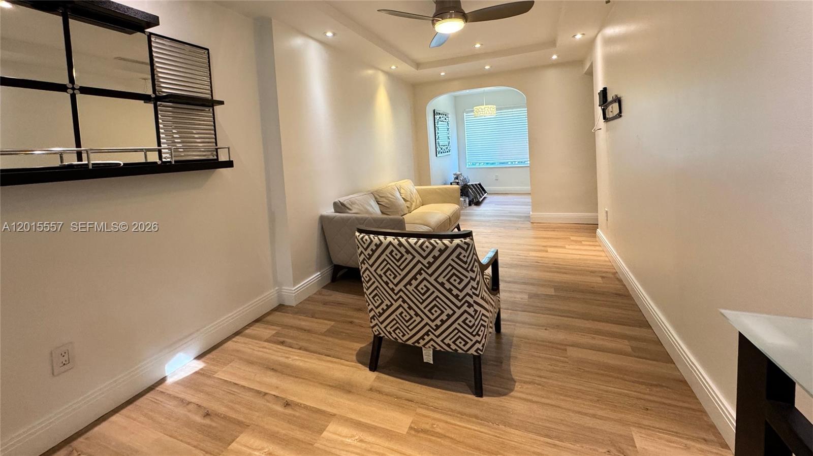 A living room features light wood flooring, a patterned armchair, a sofa, and recessed lighting — 645 Lenox Ave, Miami Beach FL 33139, MIAMI BEACH, FL