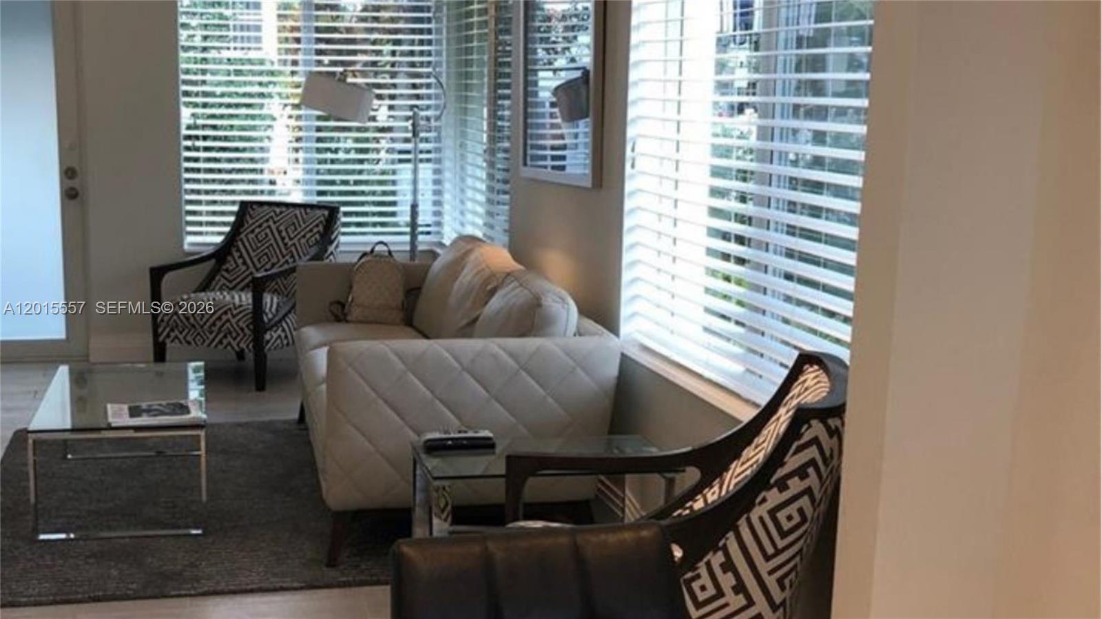 A living room features a light-colored sofa, two patterned armchairs, and a glass coffee table — 645 Lenox Ave, Miami Beach FL 33139, MIAMI BEACH, FL