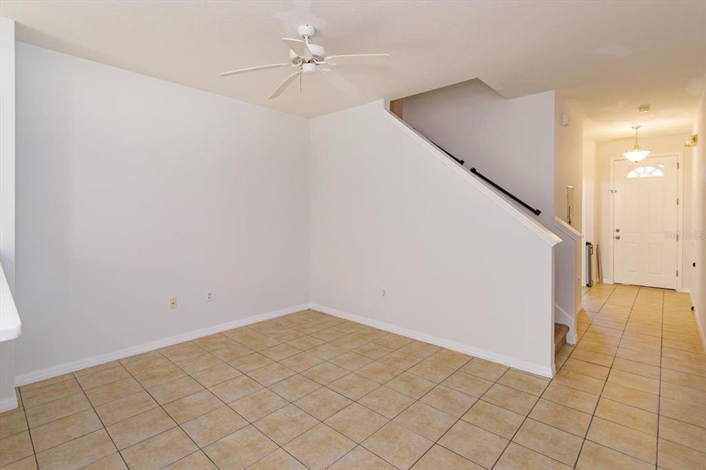 An empty room with tan tile flooring, a ceiling fan, and a staircase — 5390 PARADISE CAY CIRCLE, KISSIMMEE, FL