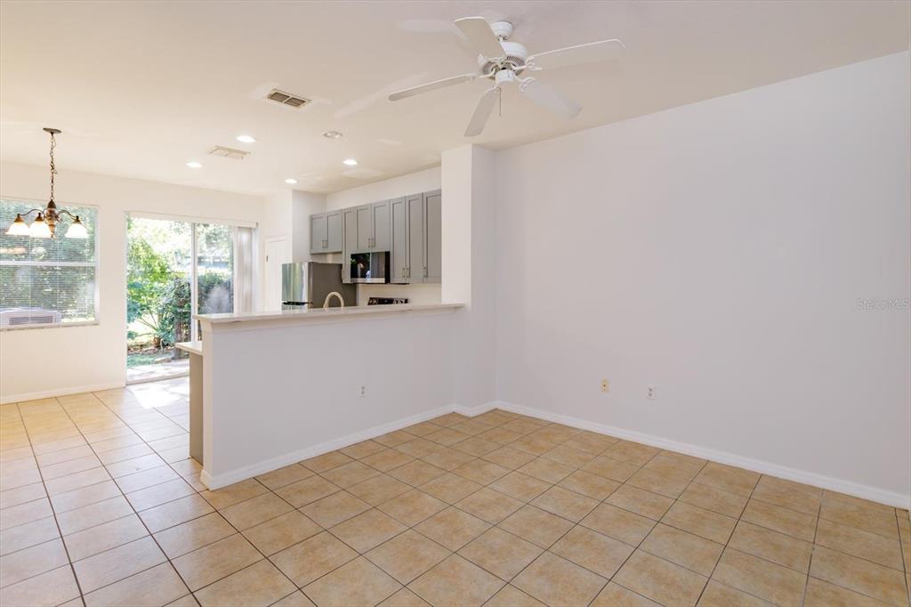 An open-concept dining area with tile flooring, a ceiling fan, and a kitchen breakfast bar — 5390 PARADISE CAY CIRCLE, KISSIMMEE, FL
