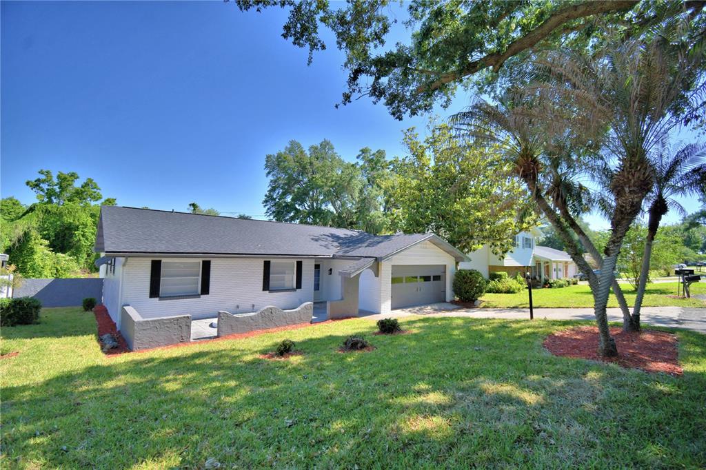 A white single-story house with a gray roof, garage, and a front yard with trees — 138 WHITTIER LANE, WINTER HAVEN, FL