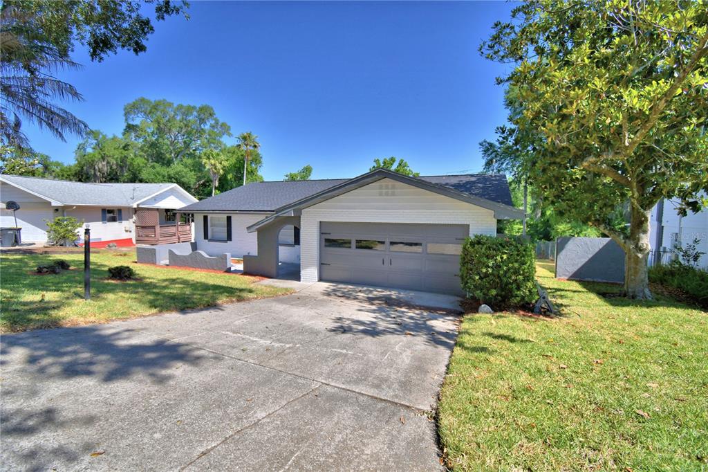 A single-story house with a white brick facade, gray garage door, and a concrete driveway — 138 WHITTIER LANE, WINTER HAVEN, FL