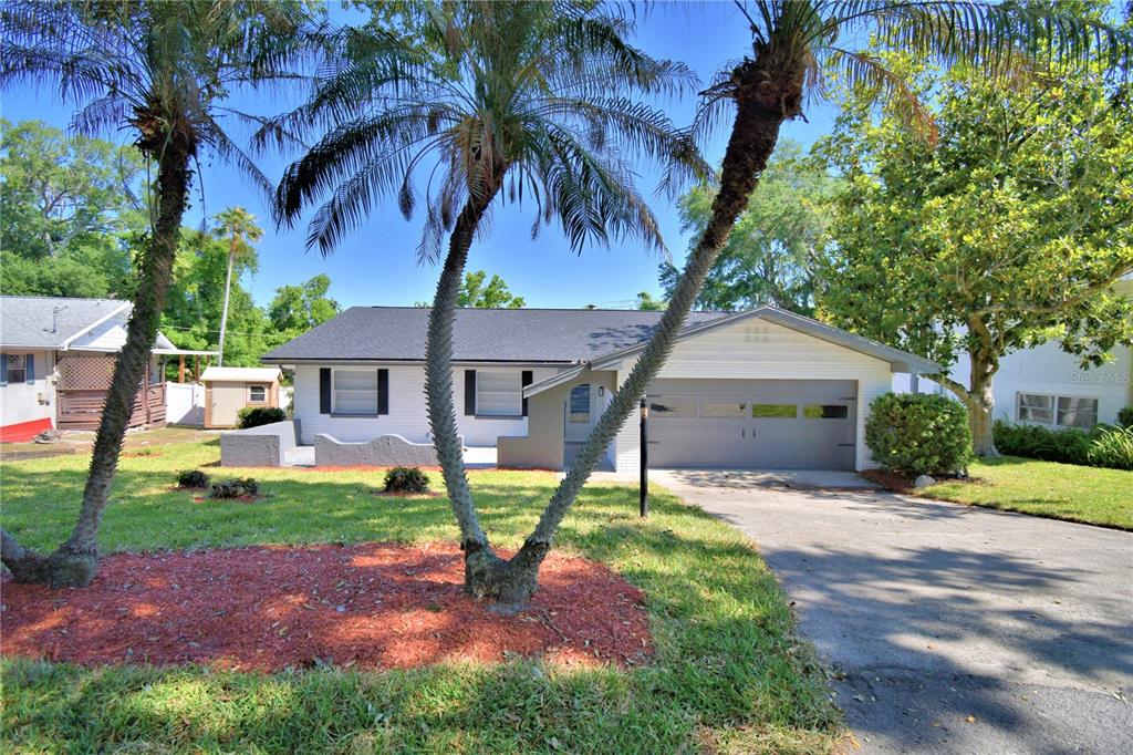 A single-story house with a white brick exterior, dark roof, and a two-car garage — 138 WHITTIER LANE, WINTER HAVEN, FL