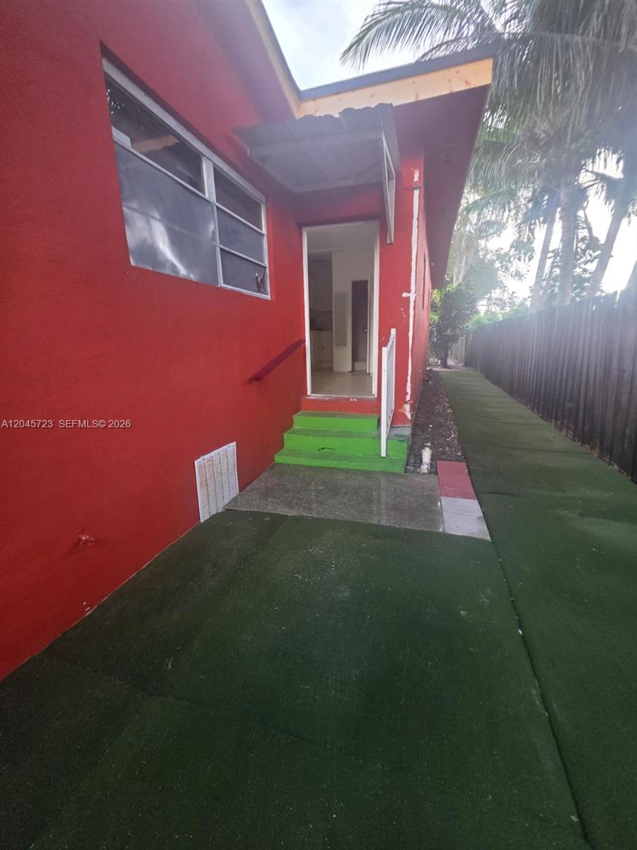 A red exterior wall features a doorway with green steps and a small awning — 10861 NW 22nd Ct # 0, Miami FL 33167, MIAMI, FL