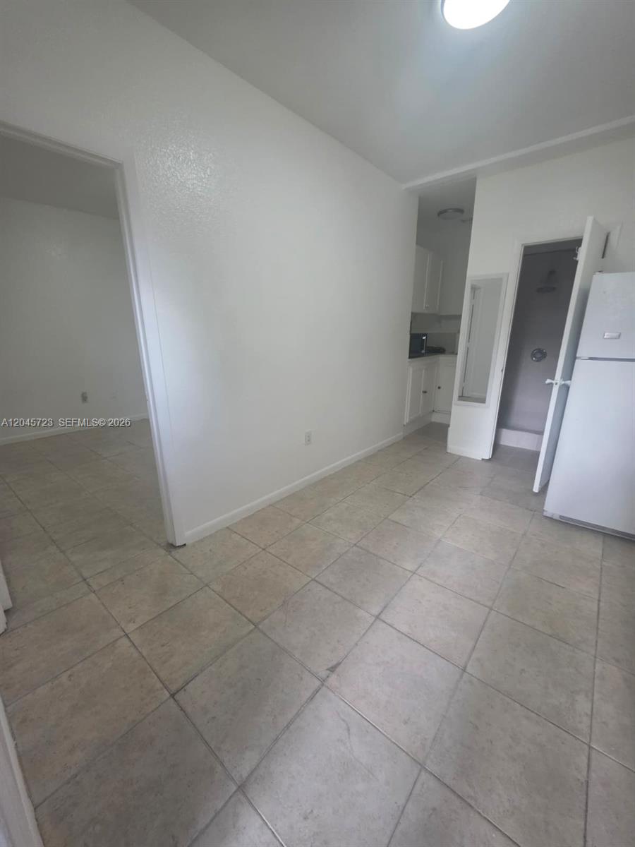 A tiled room features a doorway to a bedroom, a kitchen area, and a refrigerator — 10861 NW 22nd Ct # 0, Miami FL 33167, MIAMI, FL