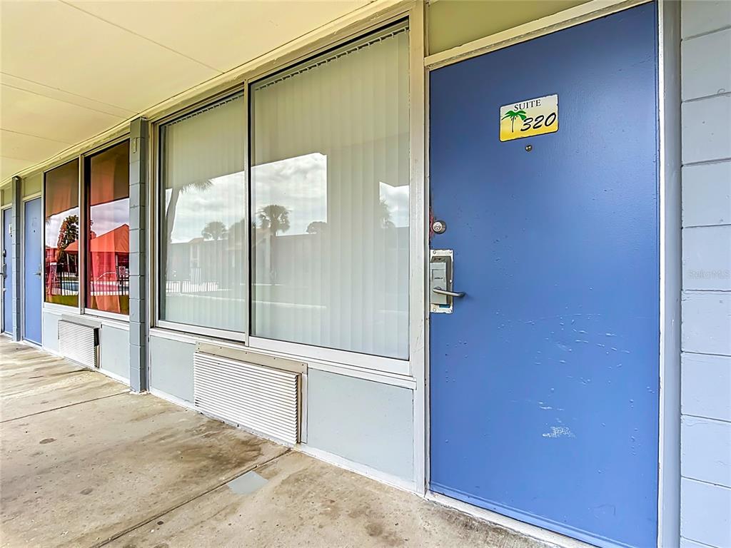 A blue exterior door labeled suite 320 sits next to a large window and walkway — 43420 HIGHWAY 27 UNIT 320, DAVENPORT, FL