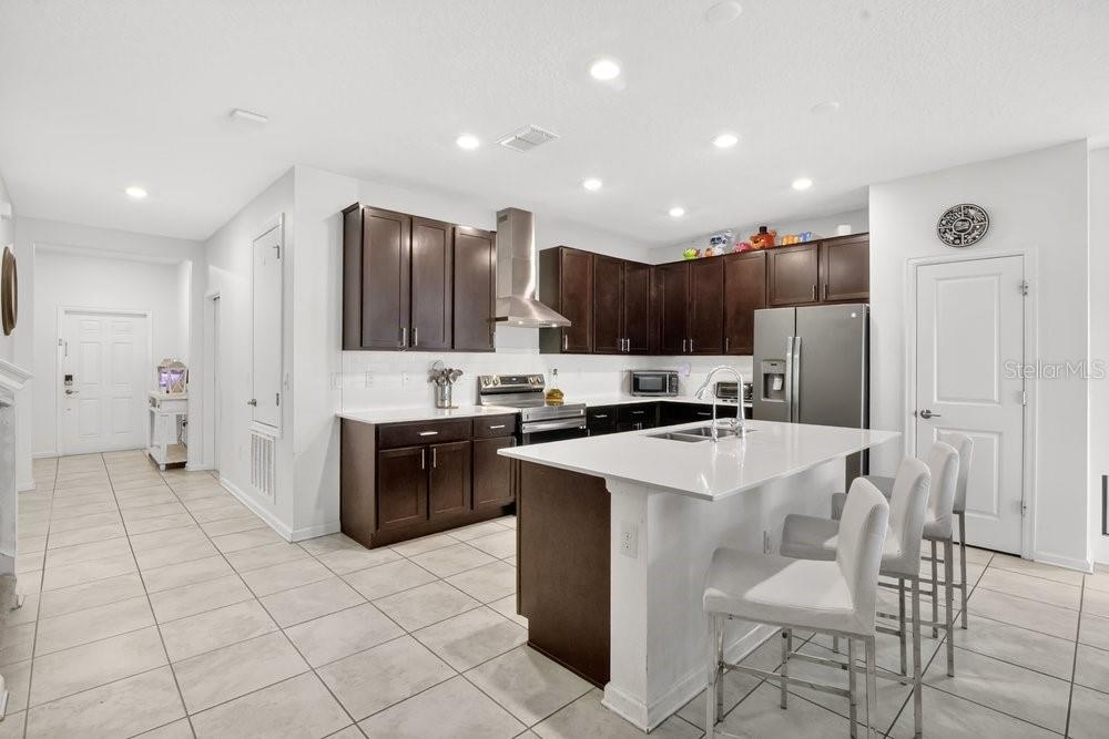 A kitchen features dark wood cabinets, white countertops, a central island, and stainless steel appliances — 2068 LIVE OAK RIDGE ROAD, KISSIMMEE, FL