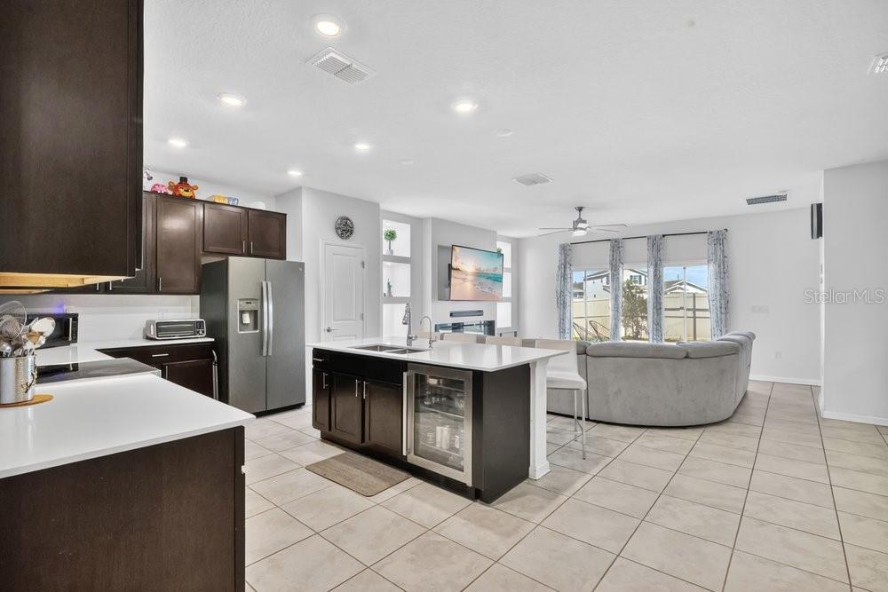A kitchen with dark cabinets and a white island opens into a living room area — 2068 LIVE OAK RIDGE ROAD, KISSIMMEE, FL