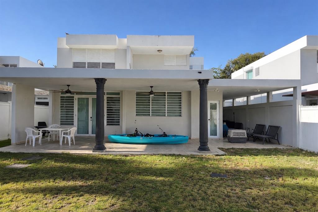 A two-story house exterior features a covered patio with columns, a kayak, and lawn furniture — 2623 CALLE PALMA DE SIERRA, PONCE, PR