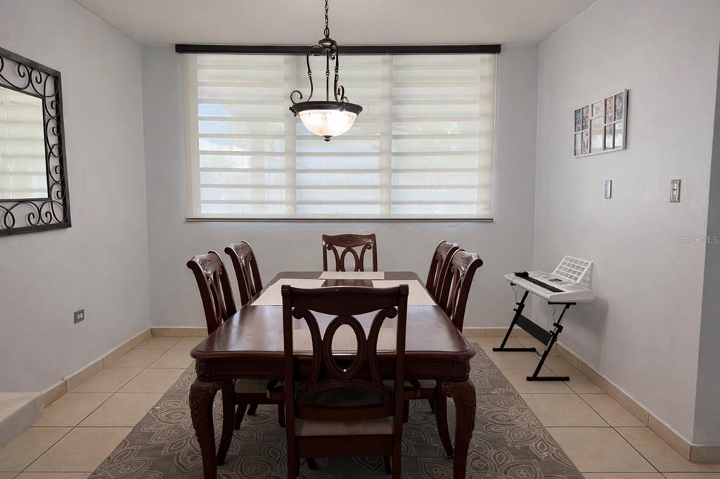 A dining room features a wooden table with six chairs, a chandelier, and a keyboard — 2623 CALLE PALMA DE SIERRA, PONCE, PR