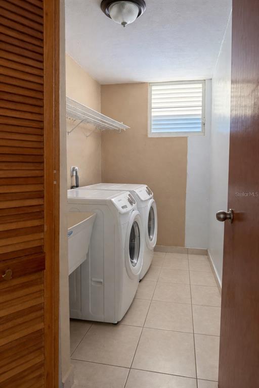 A laundry room features white front-loading appliances, a utility sink, tile flooring, and a window — 2623 CALLE PALMA DE SIERRA, PONCE, PR