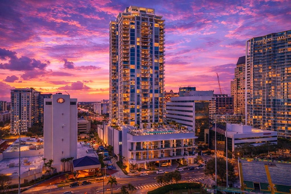 An aerial view of a tall residential skyscraper at sunset with surrounding city buildings — 301 1ST STREET S UNIT 3205, ST PETERSBURG, FL
