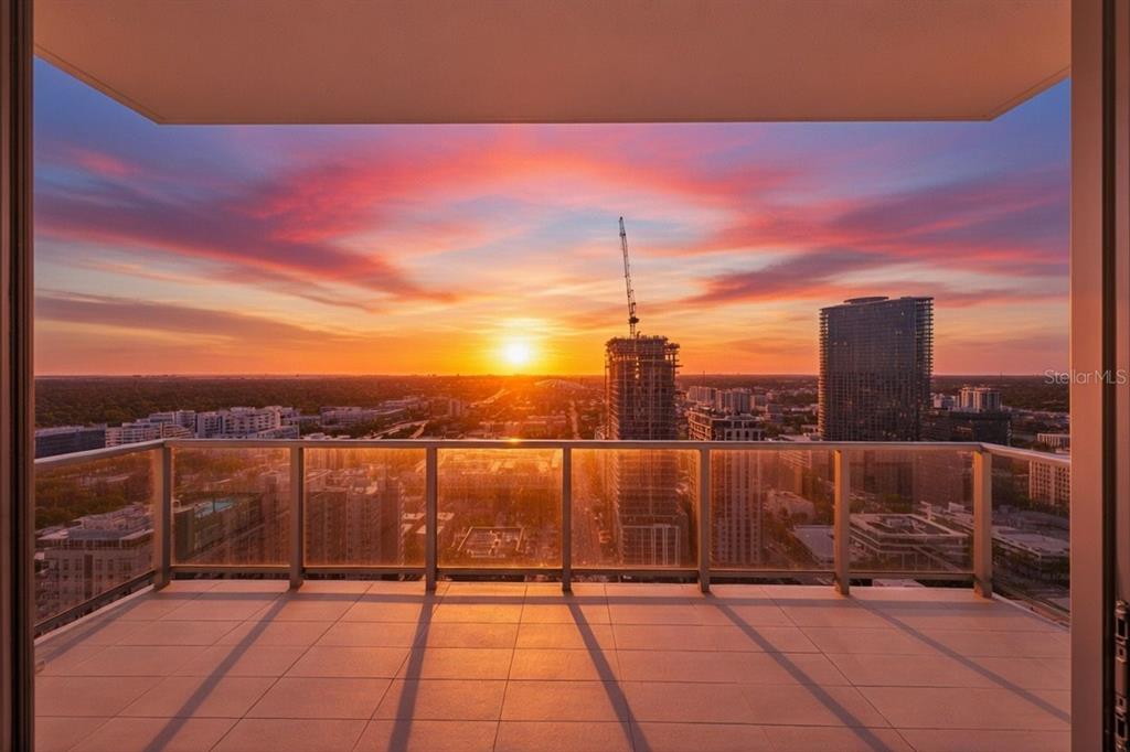 A balcony with a glass railing overlooks a city skyline during a vibrant sunset — 301 1ST STREET S UNIT 3205, ST PETERSBURG, FL