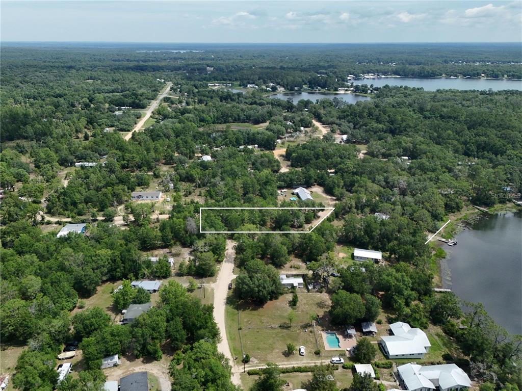 An aerial view shows a wooded residential lot outlined in white near a lake — 225 MIRROR LAKE DRIVE, INTERLACHEN, FL