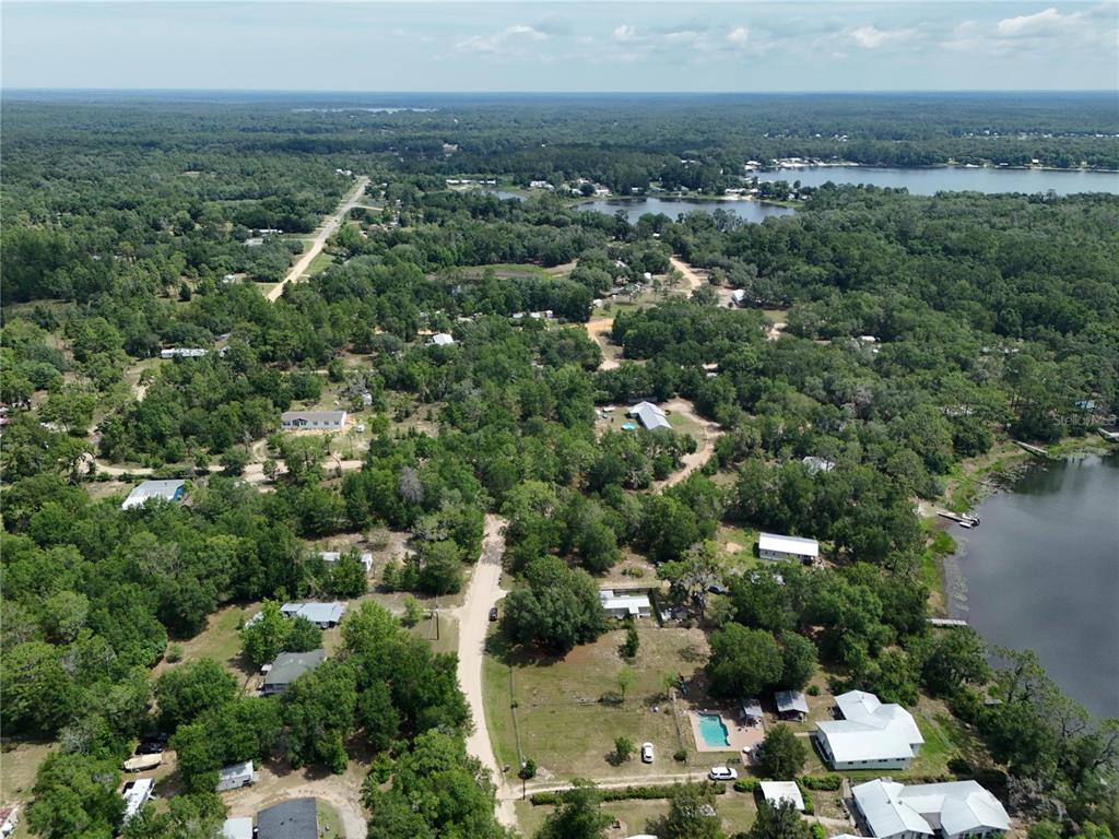 An aerial view shows a rural residential area with scattered houses, trees, and a lake — 225 MIRROR LAKE DRIVE, INTERLACHEN, FL