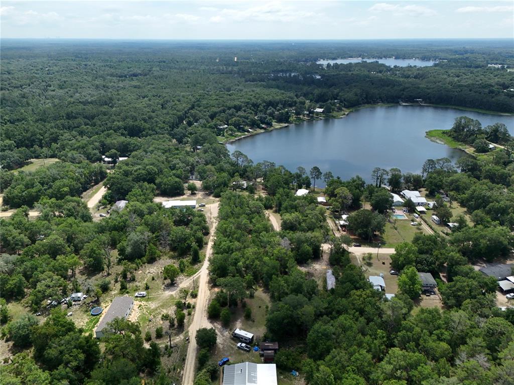 An aerial view shows a lake surrounded by dense forest and scattered residential properties — 225 MIRROR LAKE DRIVE, INTERLACHEN, FL