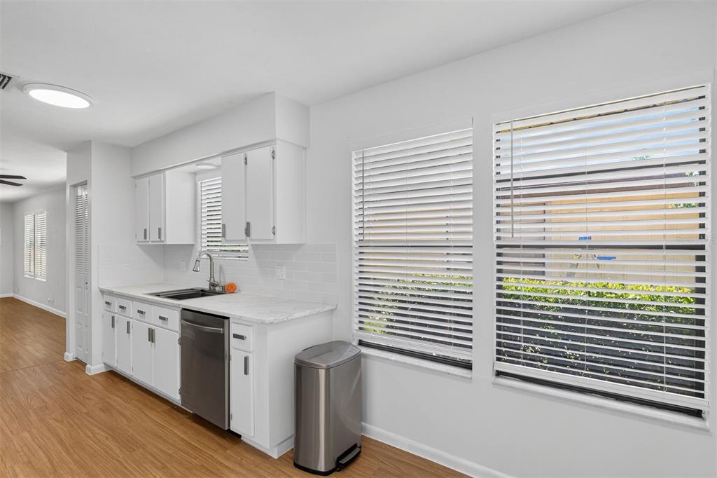 A kitchen features white cabinets, marble-look countertops, stainless steel appliances, and two windows with blinds — 8391 NW 39TH CIRCLE, GAINESVILLE, FL