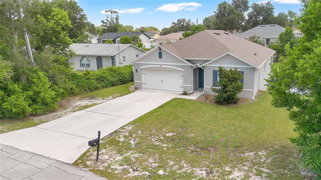 An exterior view of a single-story house with a concrete driveway and a two-car garage — 1942 MARLOW STREET, DELTONA, FL