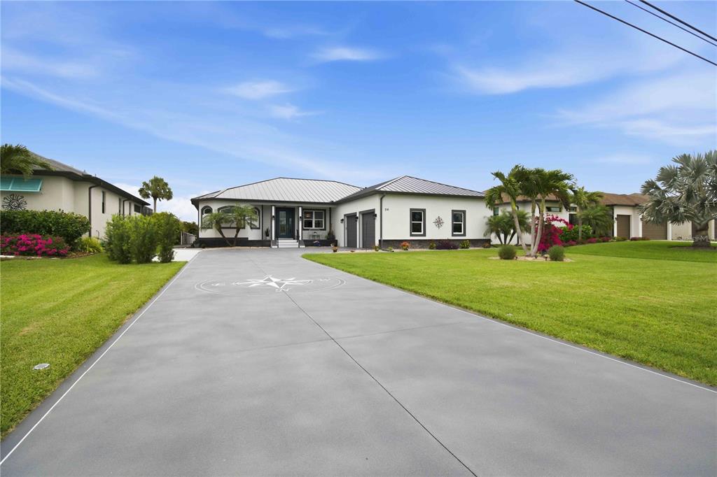 A single-story house with a metal roof and a compass rose painted on the driveway — 216 ROTONDA BOULEVARD E, ROTONDA WEST, FL
