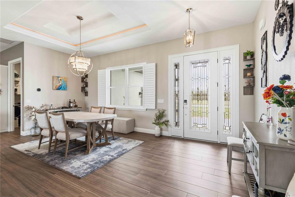 A dining area with a round table, wood-look tile floors, and a decorative front door — 216 ROTONDA BOULEVARD E, ROTONDA WEST, FL
