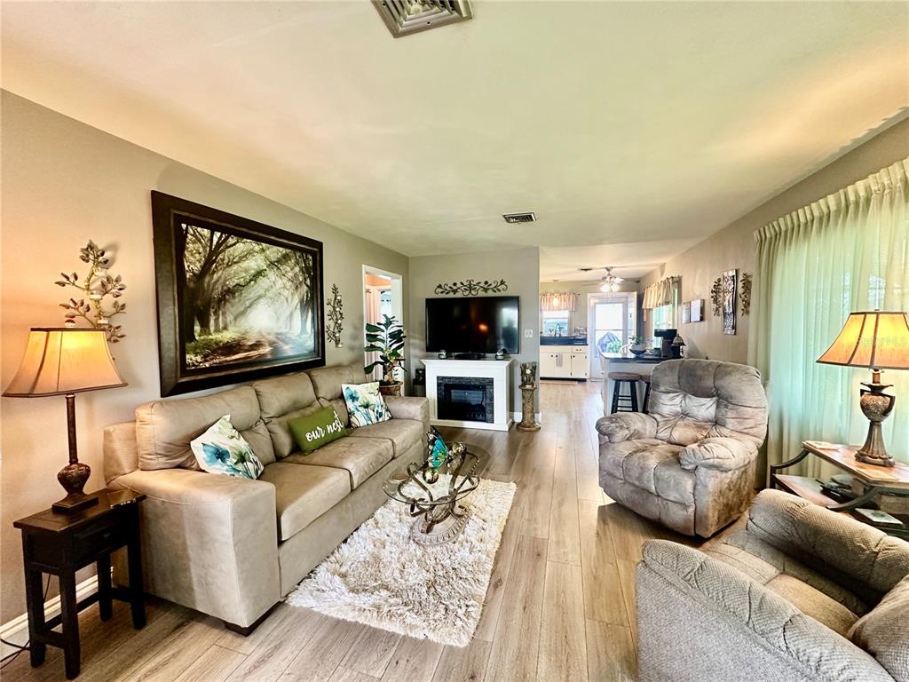 A living room features a beige sofa, two recliners, a fireplace, and wood-look flooring — 790 AVENUE Q SE, WINTER HAVEN, FL