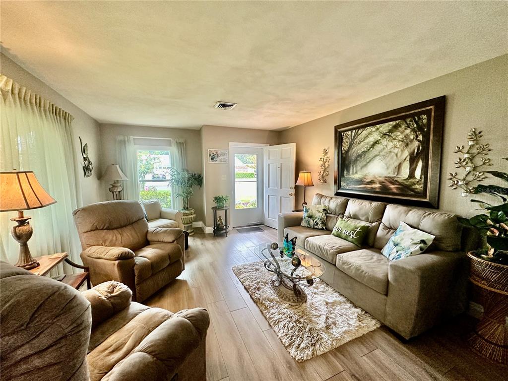 A living room features light wood-look flooring, a beige sofa, and two brown recliners — 790 AVENUE Q SE, WINTER HAVEN, FL