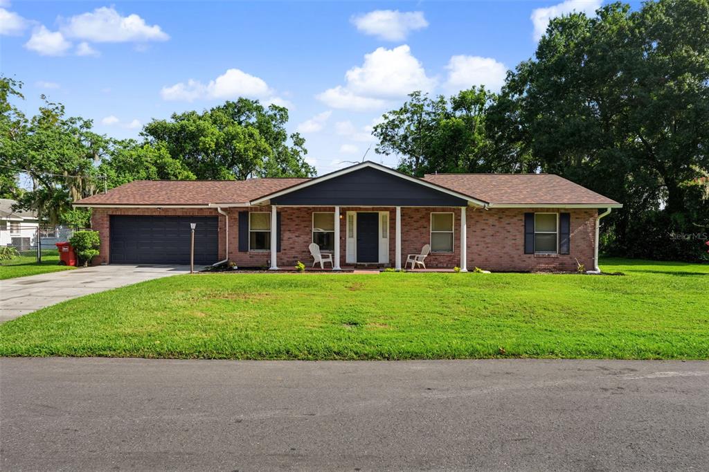 A single-story brick house with a dark garage door and a covered front porch — 1318 LOUISIANA STREET, PLANT CITY, FL