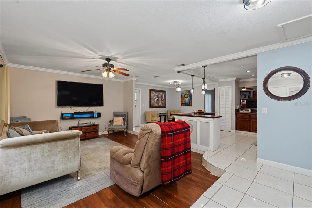 A living room with wood floors, a television, a recliner, and a tiled kitchen area — 1318 LOUISIANA STREET, PLANT CITY, FL