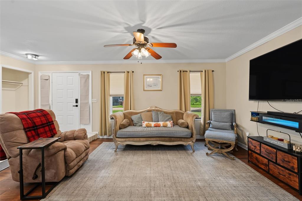 A living room features a brown recliner, a vintage-style sofa, a television, and a ceiling fan — 1318 LOUISIANA STREET, PLANT CITY, FL