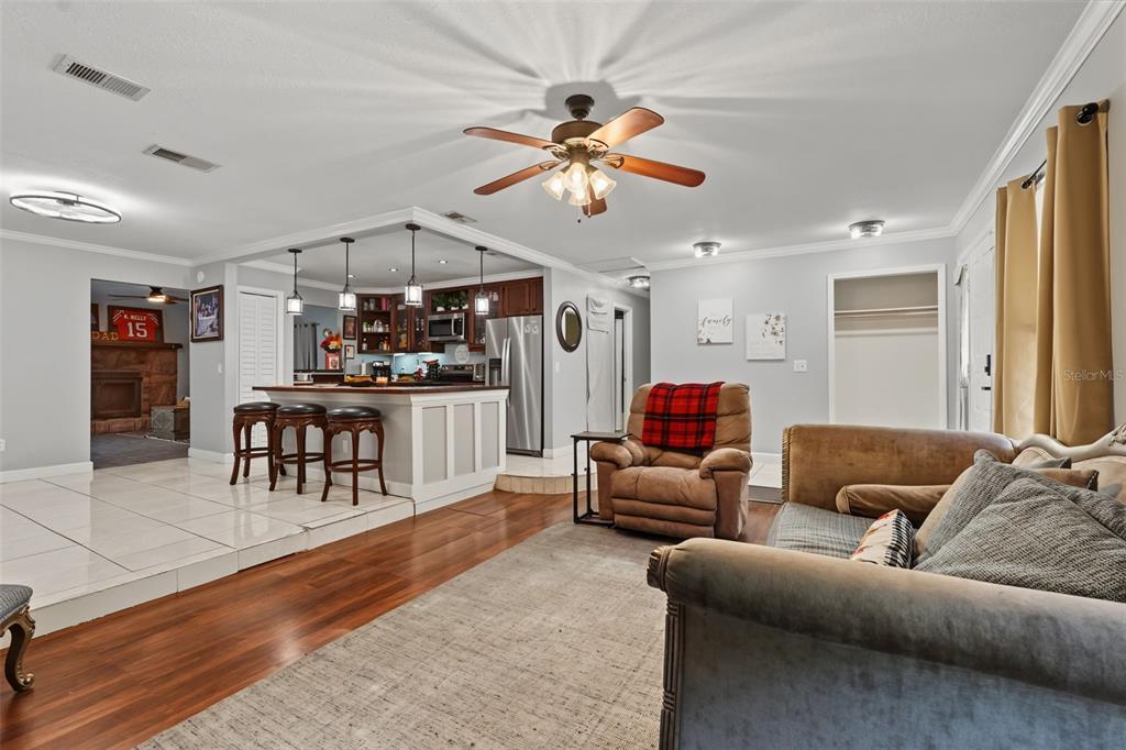 A living room with wood floors and a raised kitchen area featuring a breakfast bar — 1318 LOUISIANA STREET, PLANT CITY, FL