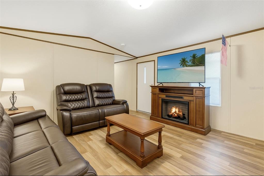 A living room features brown leather furniture, a wooden coffee table, and an electric fireplace console — 327 TINDEL CAMP ROAD, LAKE WALES, FL