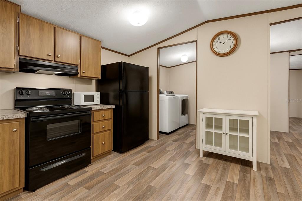 A kitchen with wood cabinets, black appliances, and a white cabinet against a beige wall — 327 TINDEL CAMP ROAD, LAKE WALES, FL