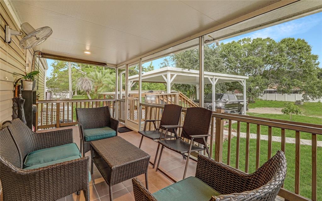 A screened-in porch features wicker furniture, tile flooring, and a view of a grassy yard — 327 TINDEL CAMP ROAD, LAKE WALES, FL