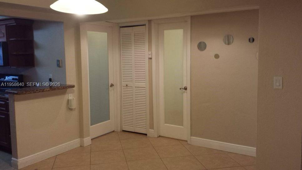 A dining area features tile flooring, two frosted glass doors, and a central louvered closet — 7368 SW 82nd St # E113, Miami FL 33143, MIAMI, FL