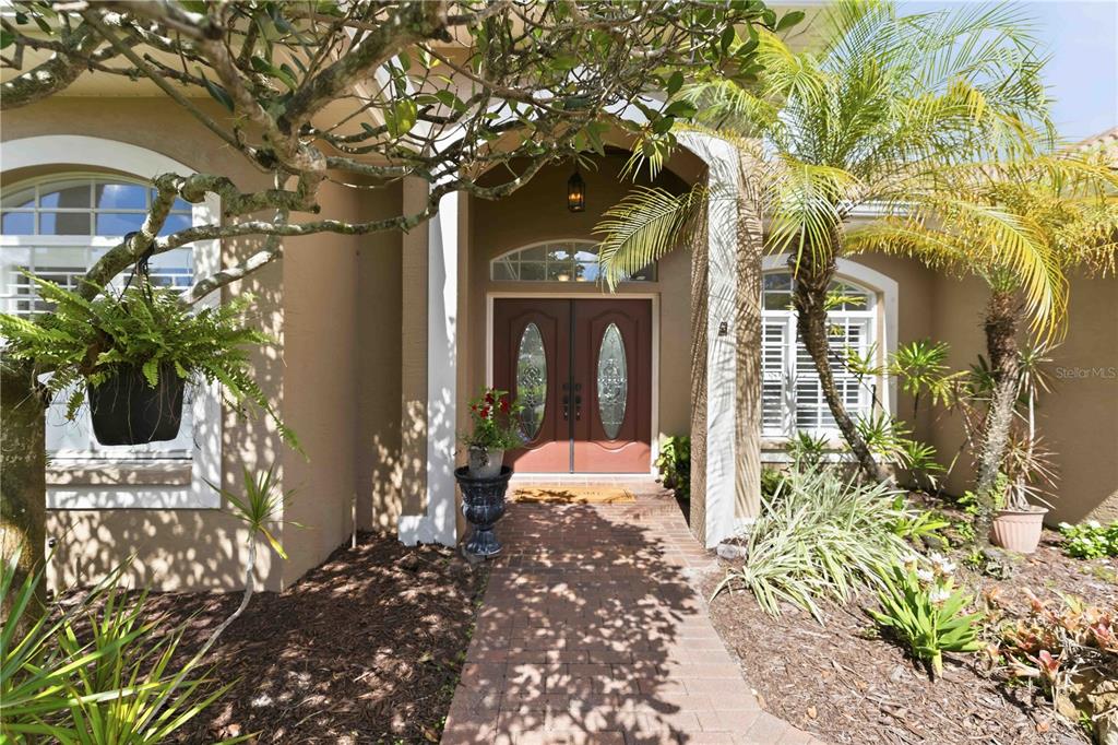 A brick walkway leads to the double front doors of a house with palm trees — 4742 OLD FARM ROAD, SARASOTA, FL