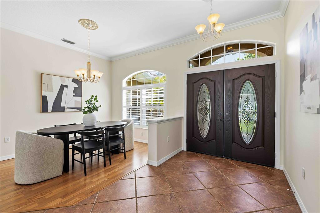 A dining area with wood floors sits next to a tiled entryway with double doors — 4742 OLD FARM ROAD, SARASOTA, FL