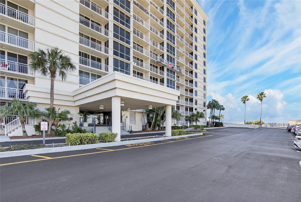 A multi-story residential building with a covered entrance and a paved parking lot — 100 PIERCE STREET UNIT 703, CLEARWATER, FL