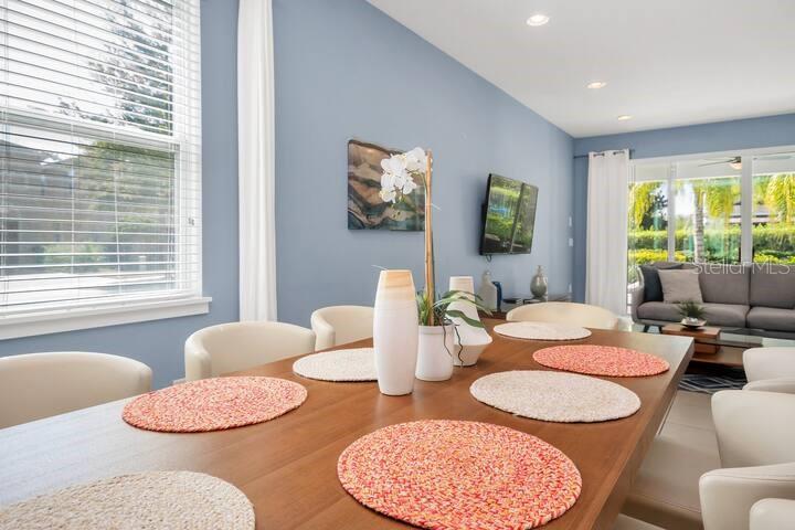 A dining area with a wooden table and chairs sits before a blue living room — 200 PENDANT COURT, KISSIMMEE, FL