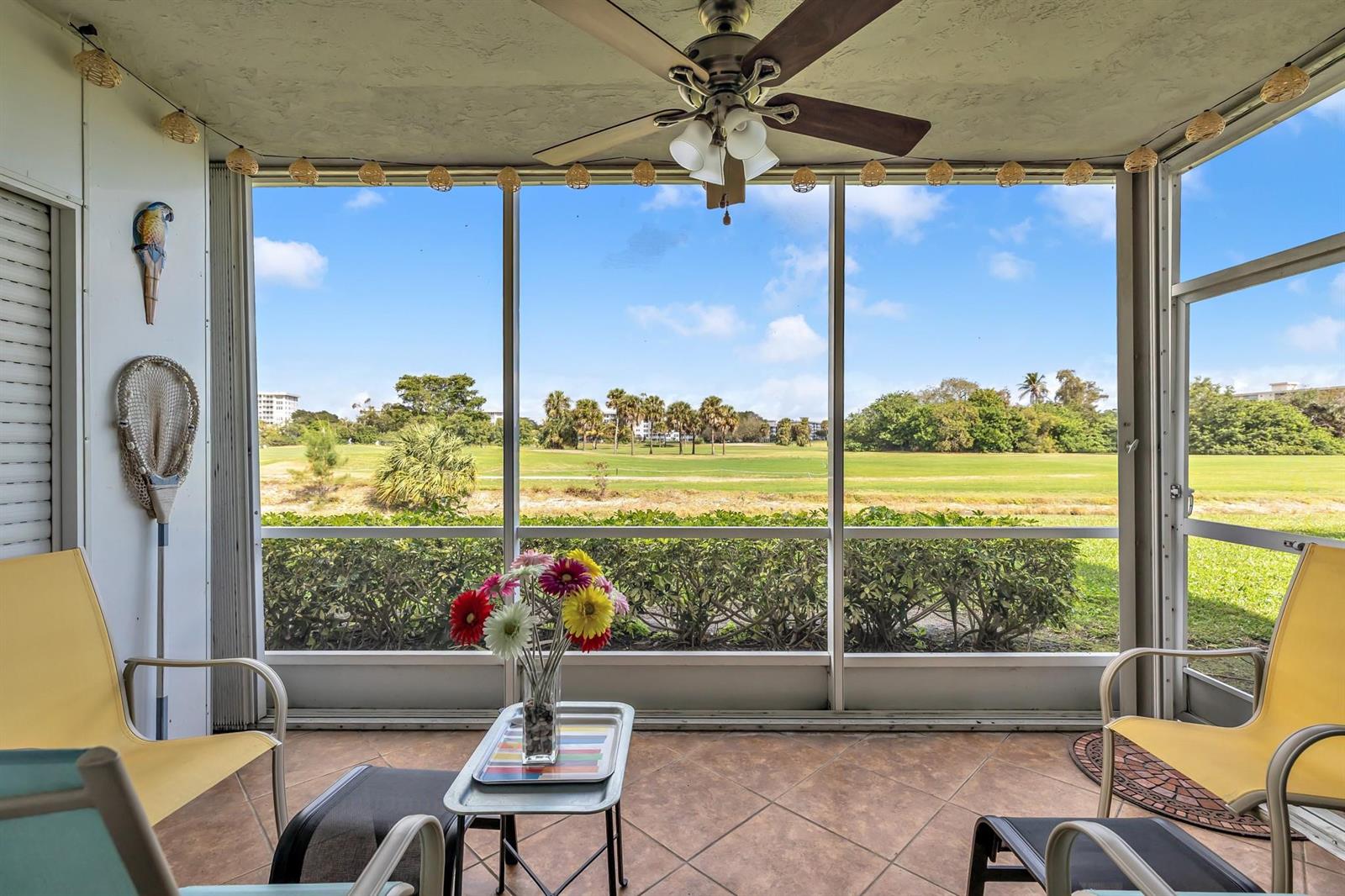 A screened-in patio features tile flooring, yellow chairs, and a view of a golf course — 3001 S Palm Aire Drive # 105, Pompano Beach FL 33069, POMPANO BEACH, FL