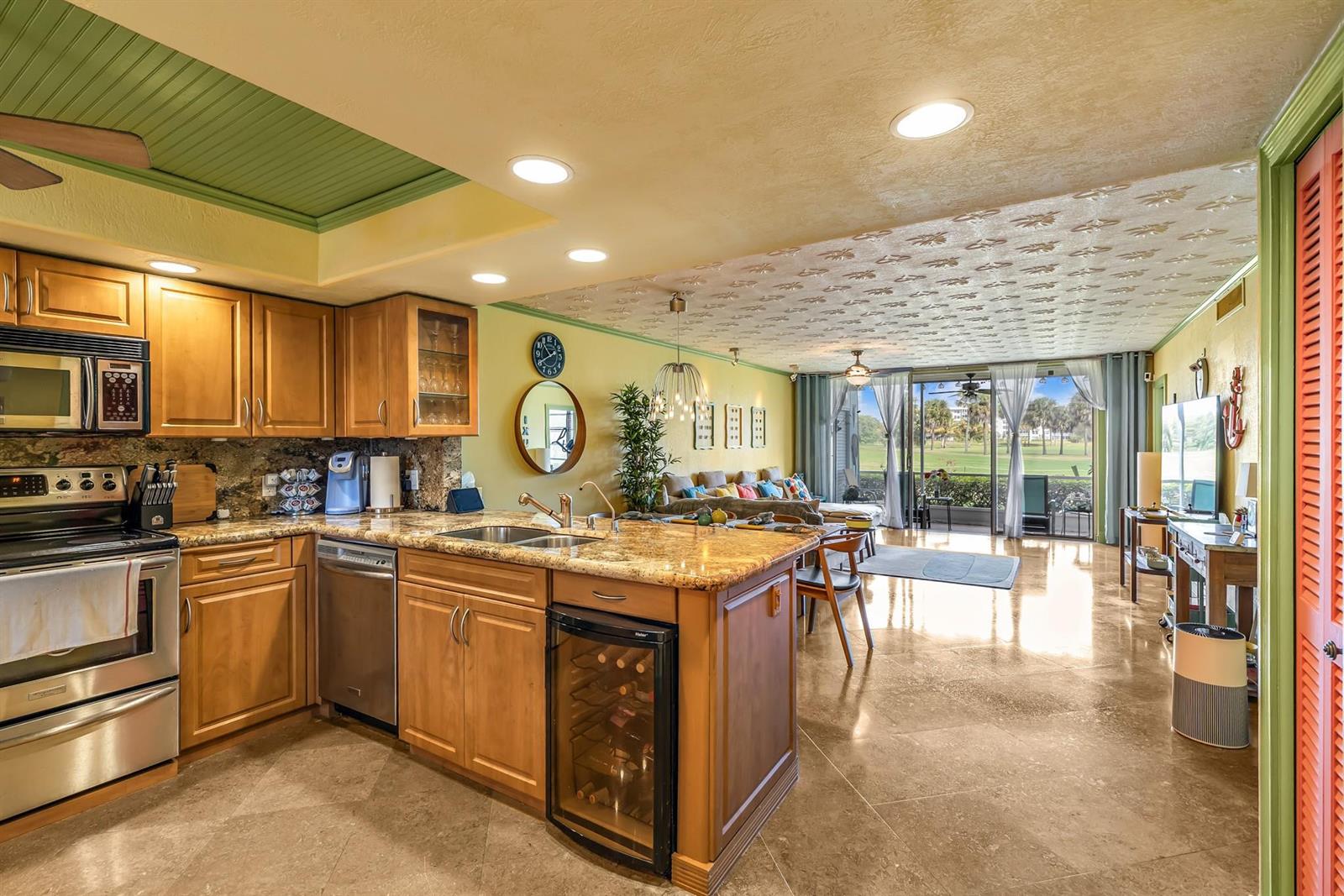 A kitchen with wood cabinets and granite countertops opens into a living area with views — 3001 S Palm Aire Drive # 105, Pompano Beach FL 33069, POMPANO BEACH, FL
