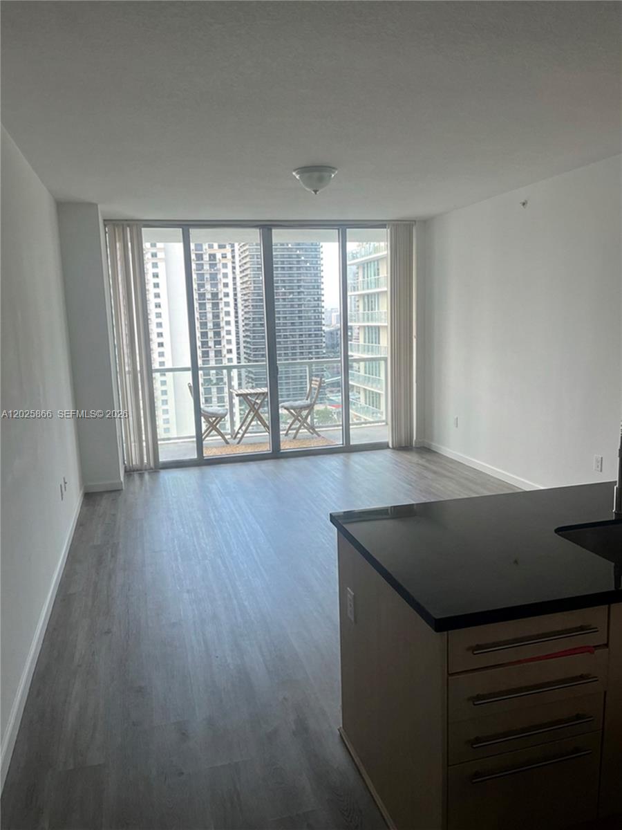 An open-concept living area features light wood-look flooring, a kitchen island, and a balcony — 79 SW 12 ST, Miami FL 33130, MIAMI, FL