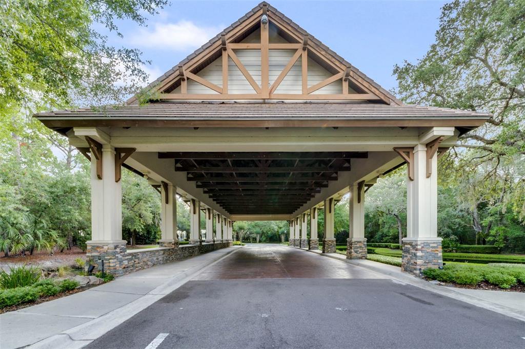 A long, covered porte-cochere features stone-based columns and a wooden truss roof structure — 25499 HAWKS RUN LANE, SORRENTO, FL