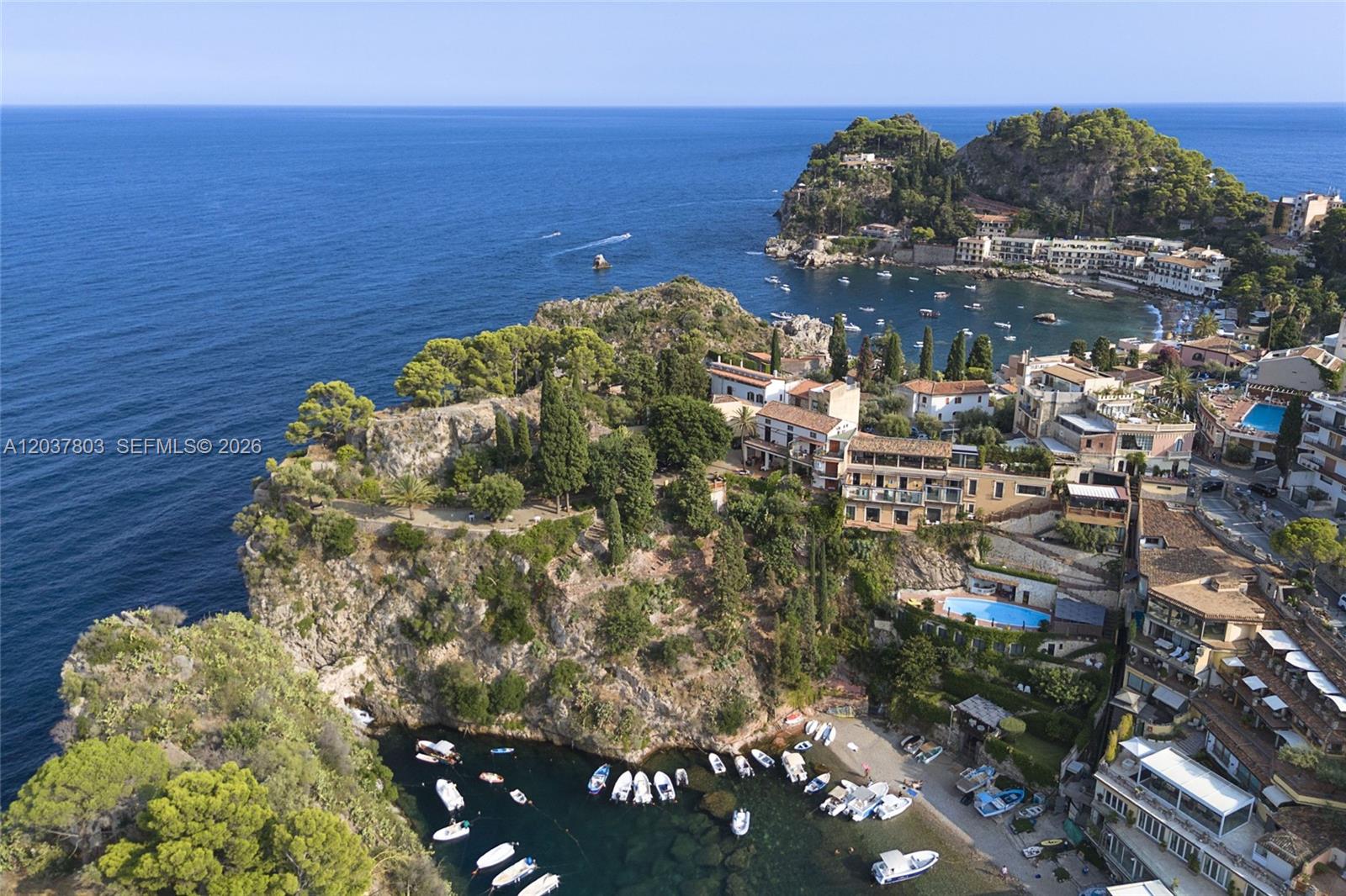 An aerial view shows a coastal cliffside with buildings, a small harbor, and boats — 1 Mazzaro, FL, FL