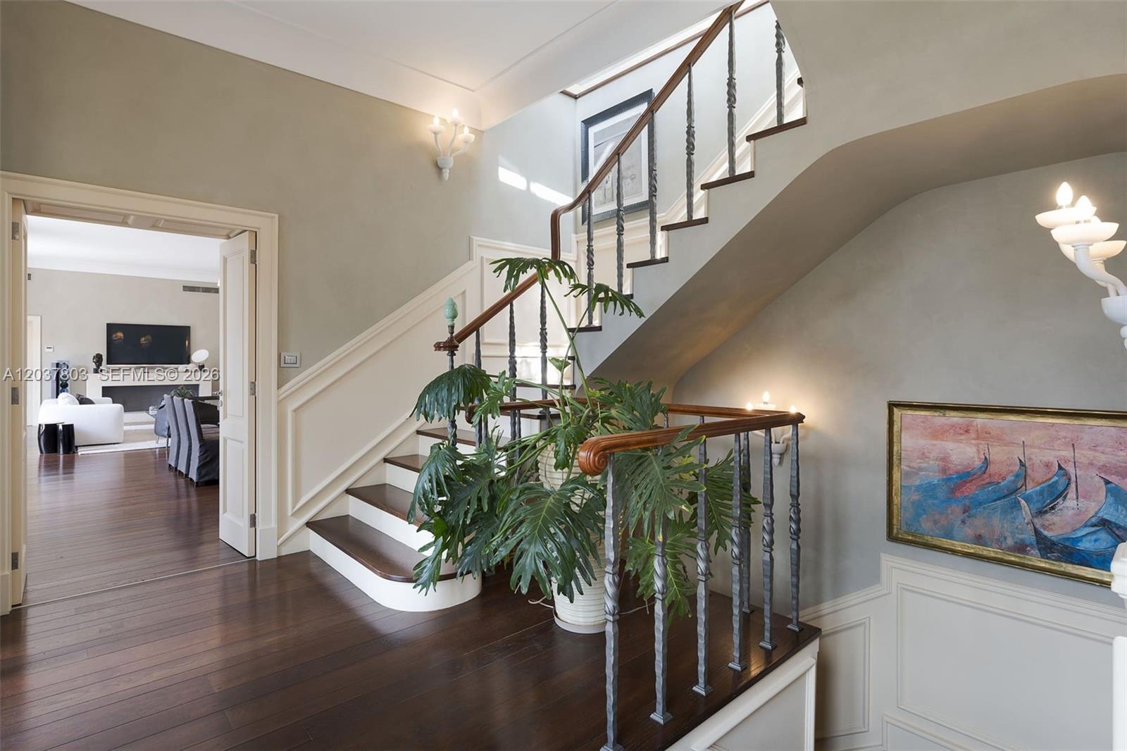 A grand staircase with dark wood treads and metal railings sits in a foyer — 1 Mazzaro, FL, FL