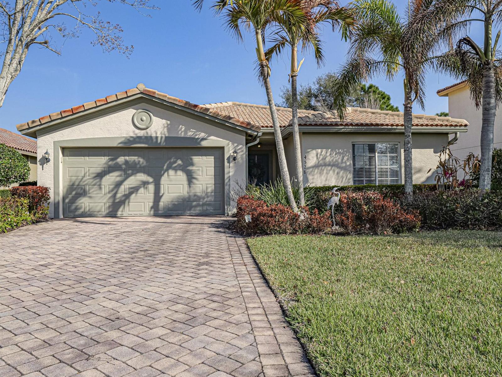 A single-story house with a paved driveway, a two-car garage, and palm trees in front — 4528 56th Lane, Vero Beach FL 32967, VERO BEACH, FL