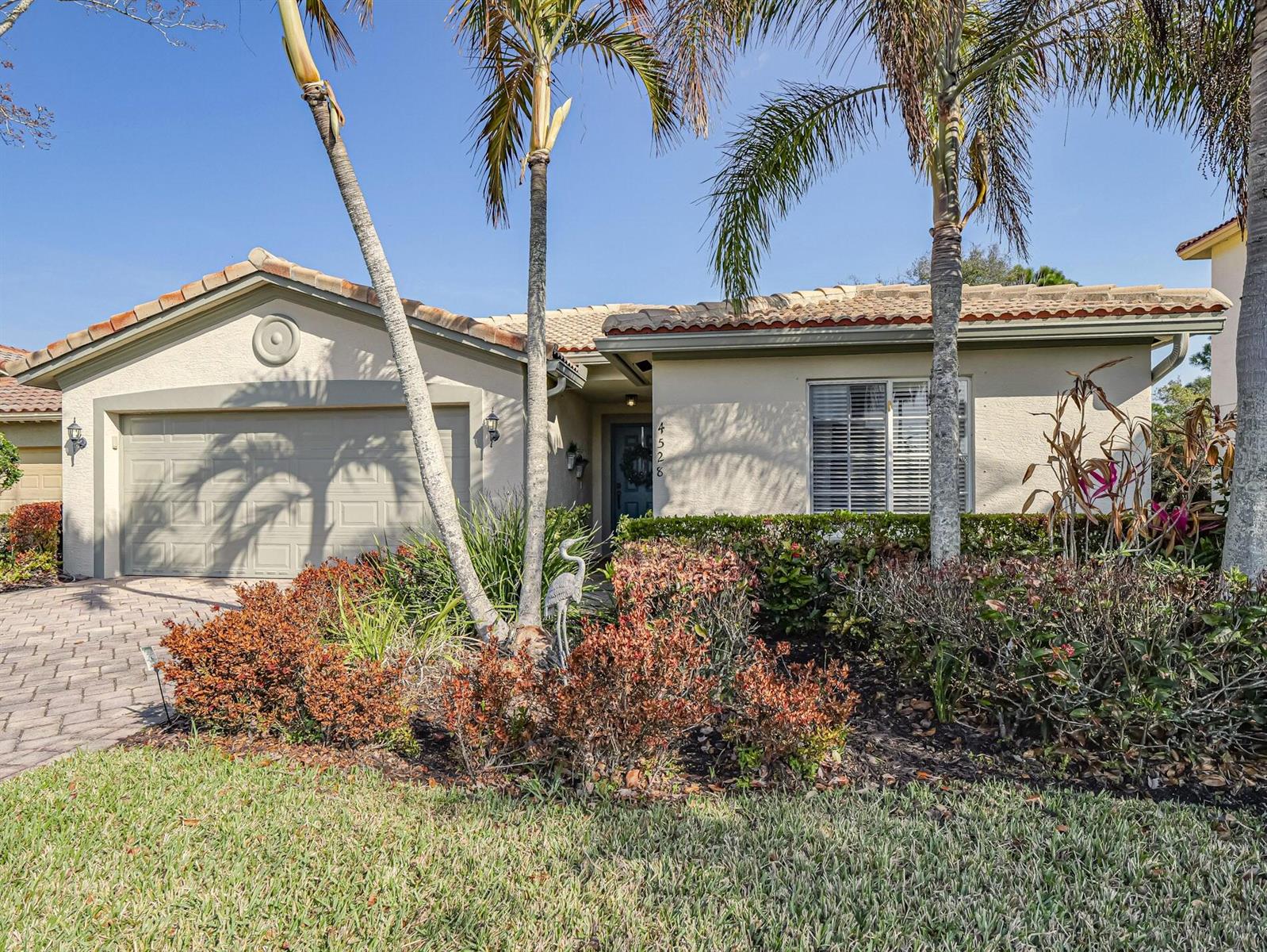 A single-story house with a beige stucco exterior, a tiled roof, and a paved driveway — 4528 56th Lane, Vero Beach FL 32967, VERO BEACH, FL